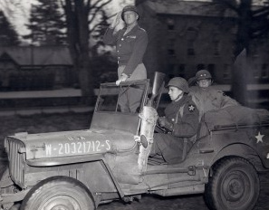 General Patton in his jeep upright
                                saluting his troops in Normandy, 1944