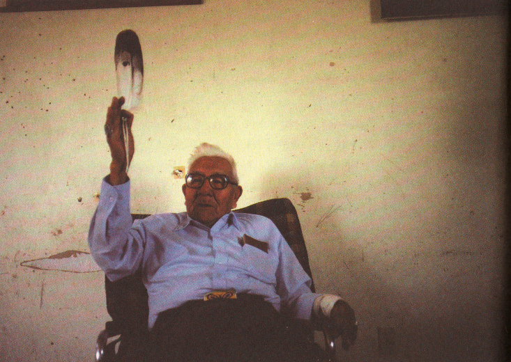 Noble Red Man
                (Mathew King) im Stuhl mit Feder in der Hand, 1987 ca.
