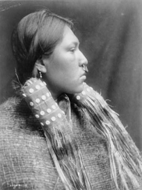 Nuu-chah-nulth-Frau mit
                                      Nasenring und in
                                      Holzfaserkleidern, Profil, ca.
                                      1910