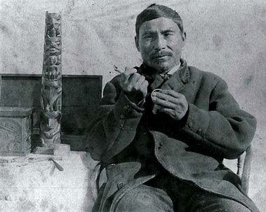 Charles
                  Edenshaw mit einem kleinen Totempfahl und mit
                  Schnitzwerkzeugen in der Hand
