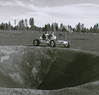 Irvin (links) und Scott (rechts) mit
                            Trainings-Mondauto "Grover" (Lunar
                            Roving Vehicle Simulator, "1g
                            trainer") auf einer geologischen
                            Exkursion im Kraterfeld von Cinder Lake in
                            Arizona am Rand eines 30 Fuss tiefen
                            Karters, 2.-3.11.1970.