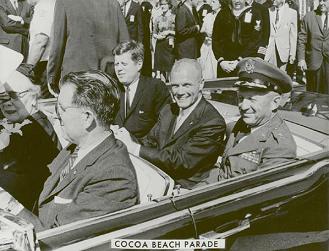 Glenn with Kennedy in a cabriolet
                            during the car parade in Cocoa Beach.