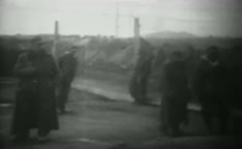 Deutsche Kriegsgefangene stehen in dicken
                        Mäneln auf trockenem Erdboden in
                        Stacheldraht-Käfig: 17min. 26sek.