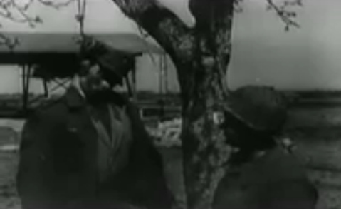 Ein Mann hängt an einem Baum, präsentiert
                        von einem Ami-Soldat, Nahaufnahme: 24min.25sek.