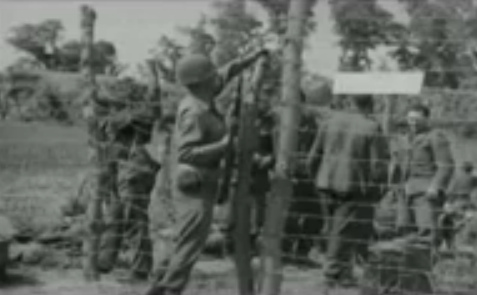 Soldado guardián "americano"
                          con un fusil en su mano cerrando una puerta de
                          alambre espinoso